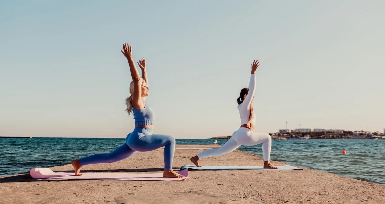 2 Women doing Yoga by the sea
