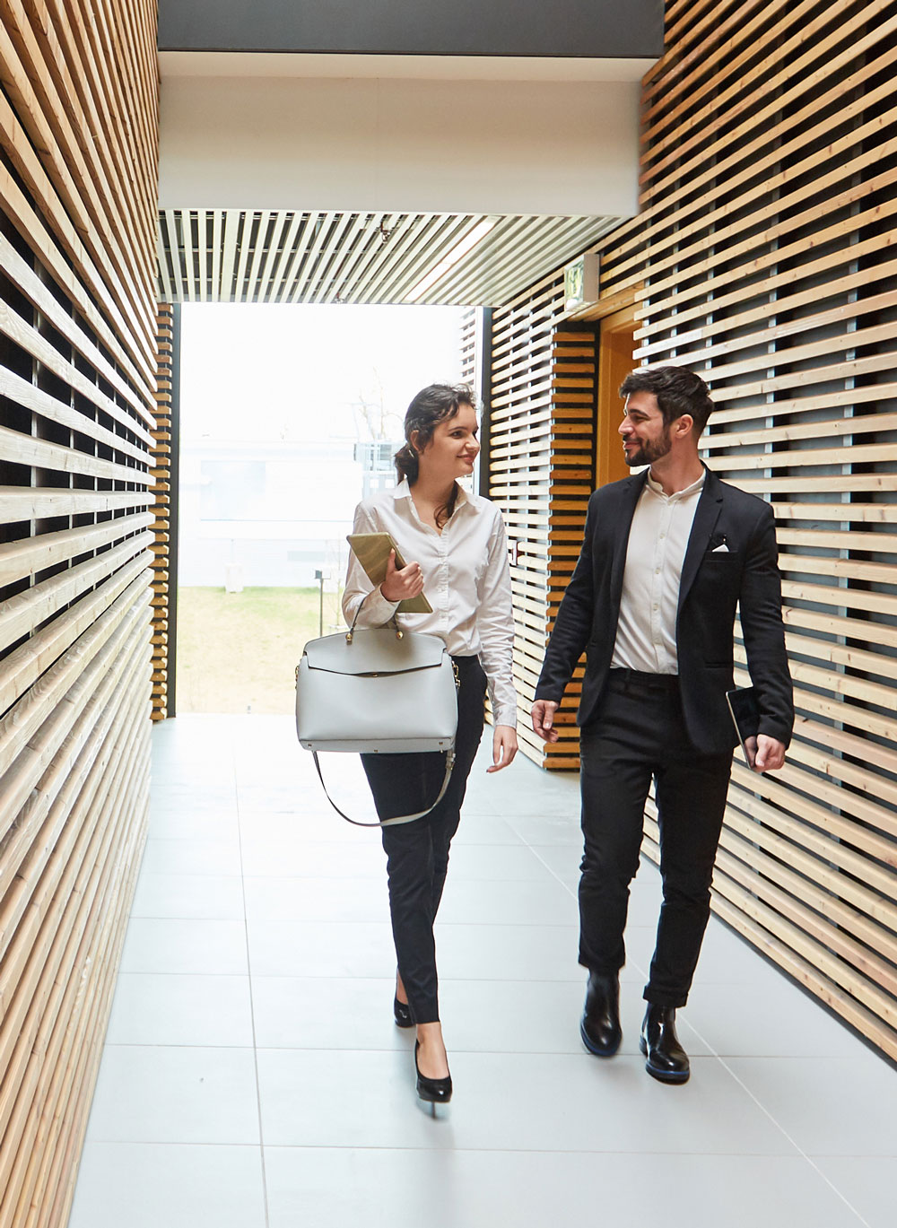 Digital Enablement visual of two people walking down a hall in an office building.