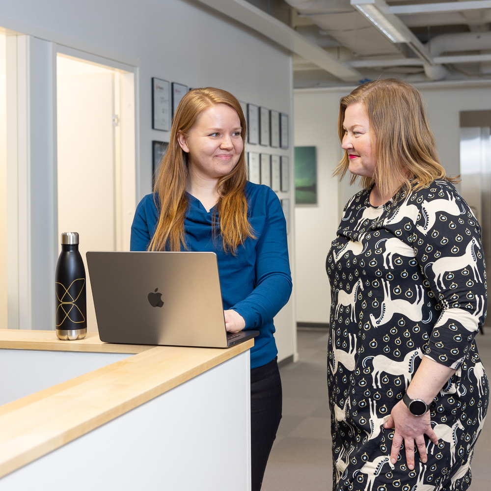 Vaimo employees working with a laptop and smiling.