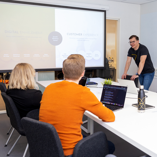 Vaimo employees happily participating in a meeting in a conference room.