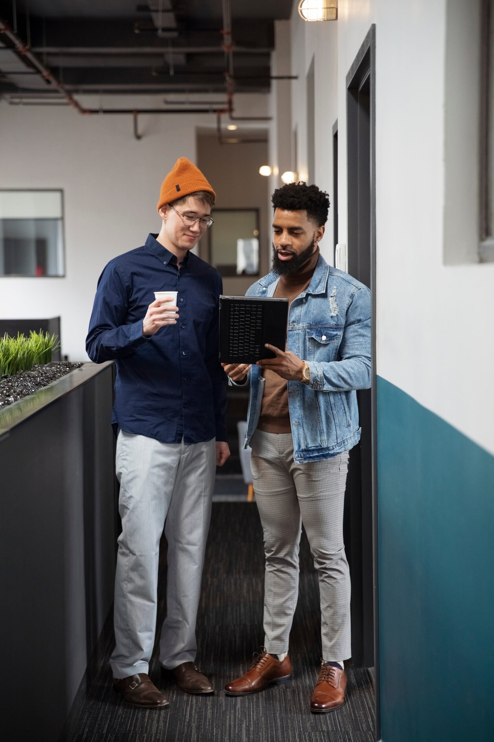 Image of two men drinking coffee and working on a laptop.