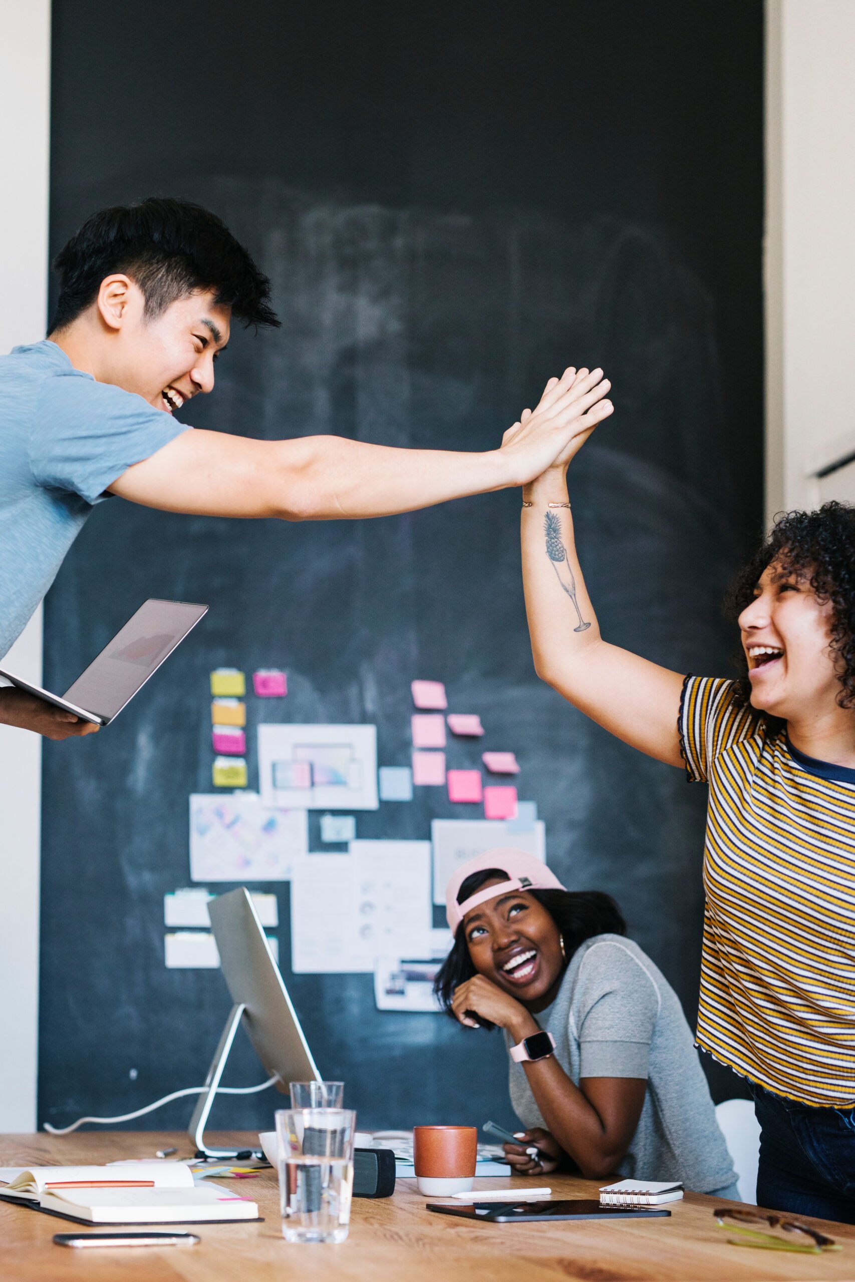 Happy team members high-fiving one another in an office.