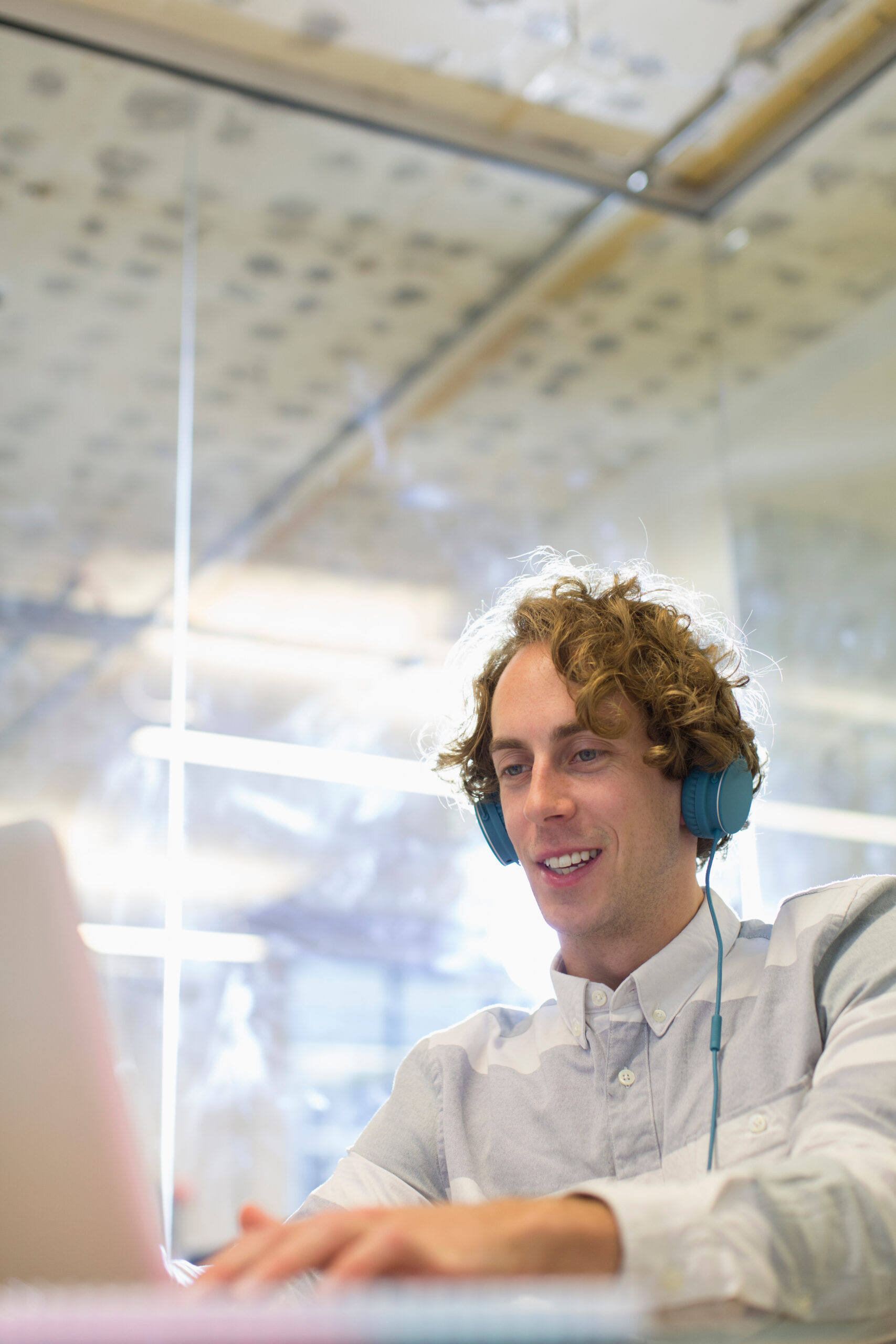 Man working behind a computer and wearing headphones.