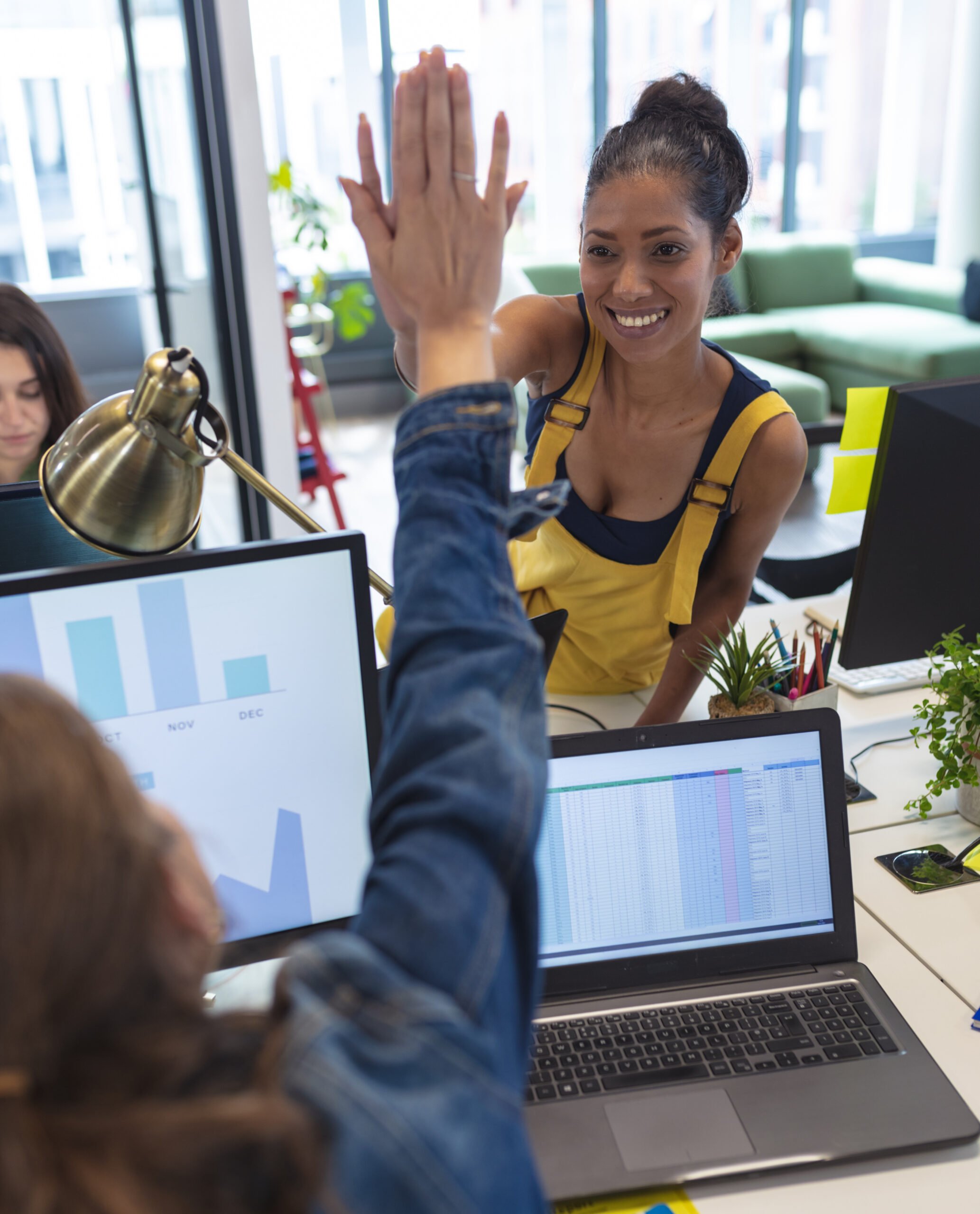 Two women high-fiving at work.