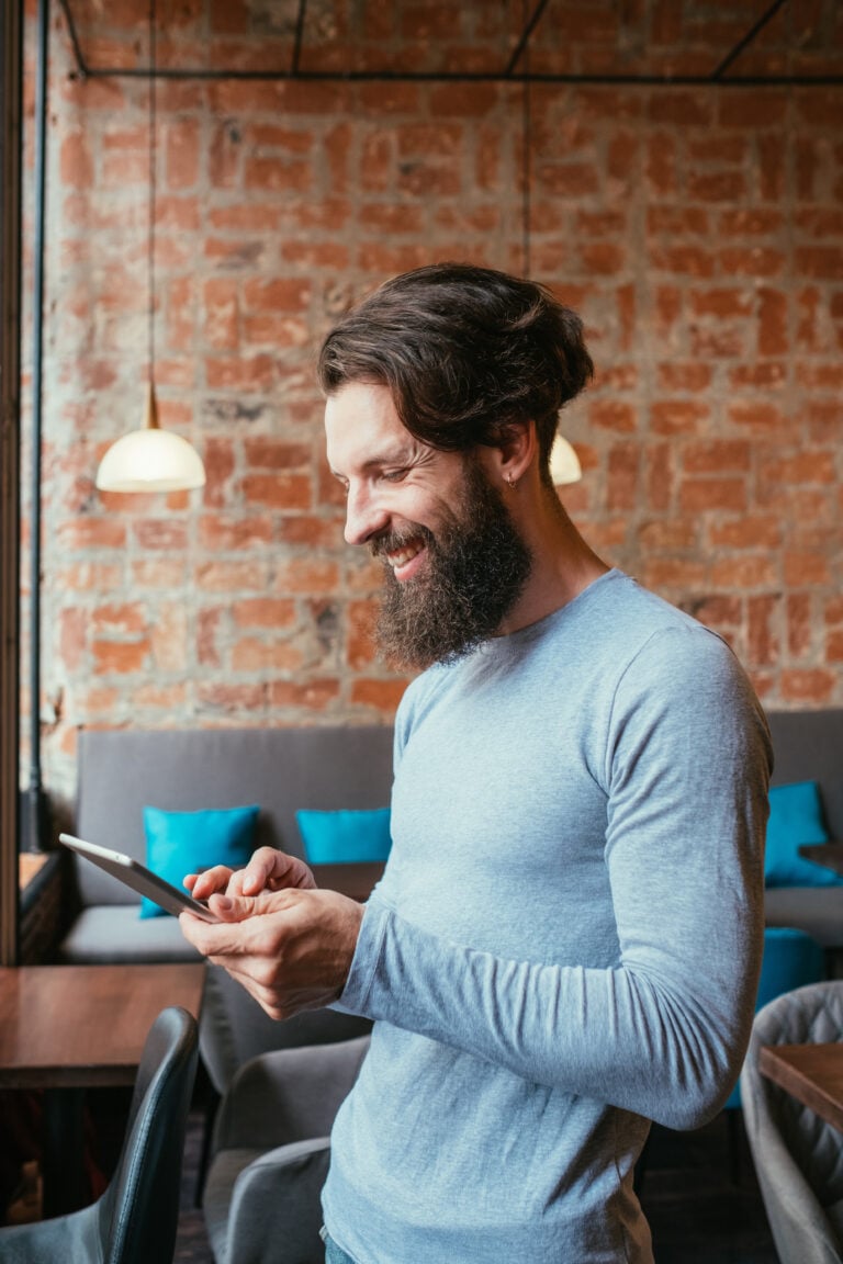 Happy older man with an alterative haircut happily shops on his mobile phone, presumably because of the amazing digital experience the ecommerce store offers him.