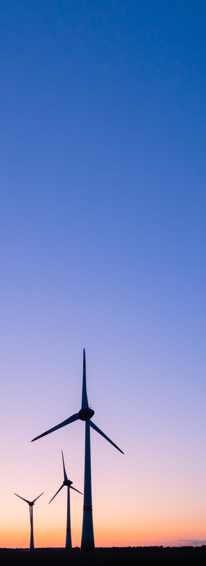 Image of wind powered windmills against a moody skyline