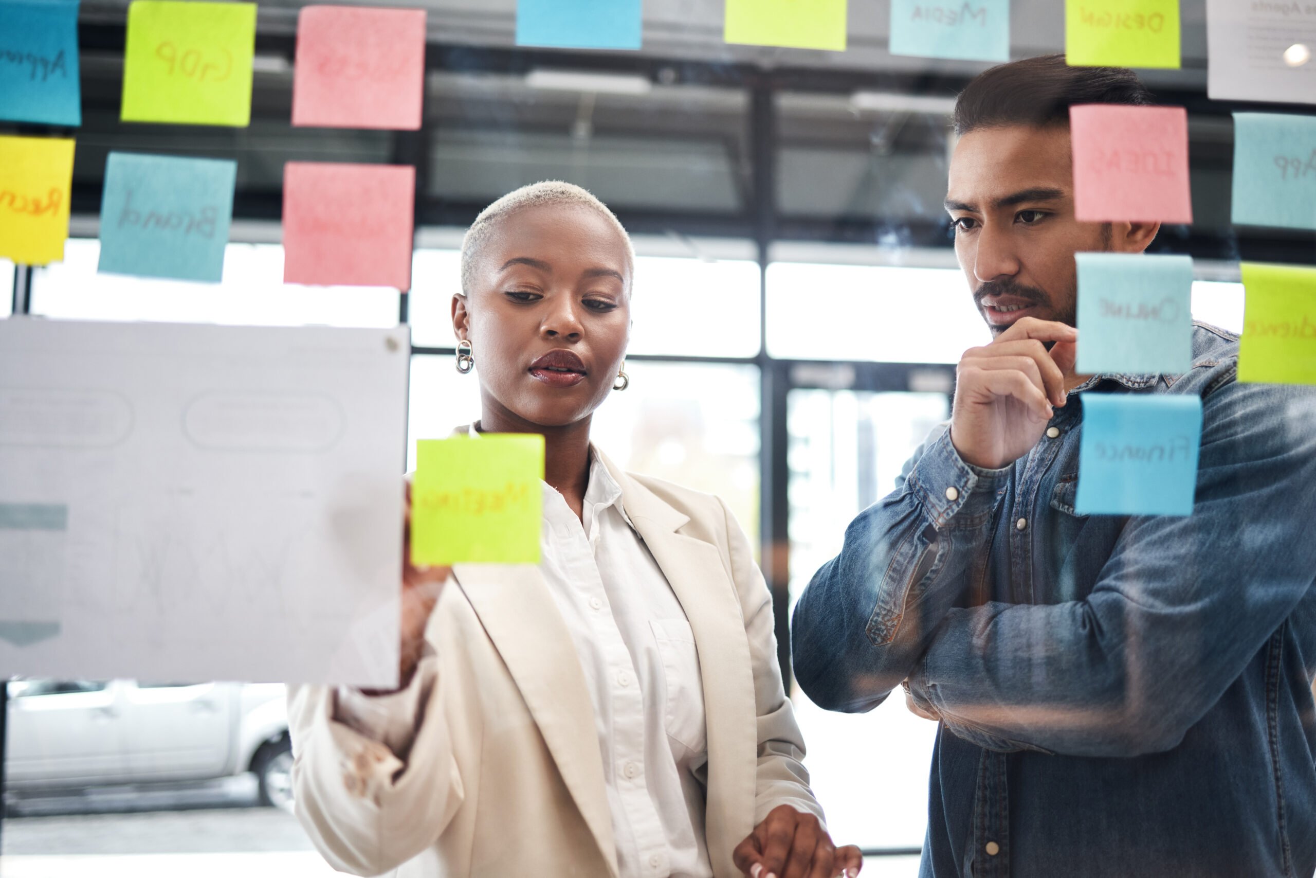 A man and woman looking at paper notes on a board together