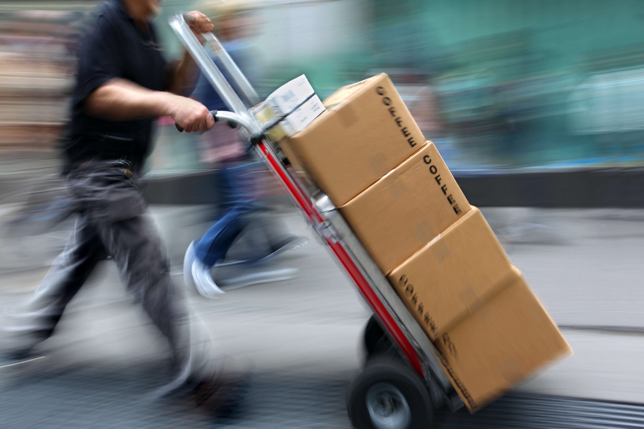 Image of delivery man pushing a trolley with packages piled on it