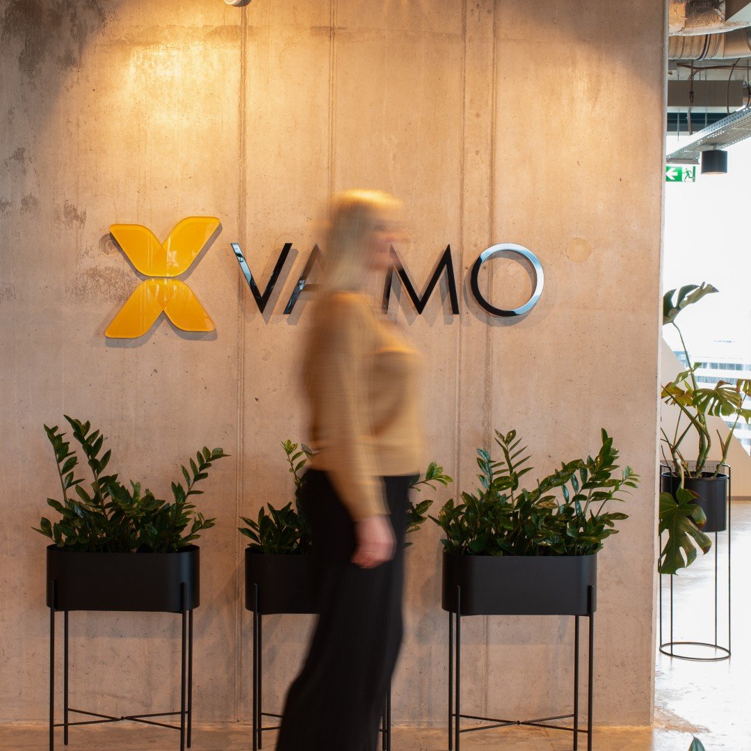 Blurry image of Vaimo employee in Vaimo office with Vaimo logo in the backdrop