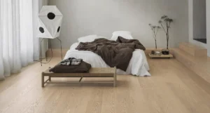 image on bedroom with bed with white sheets and brown throw on hardwood floor