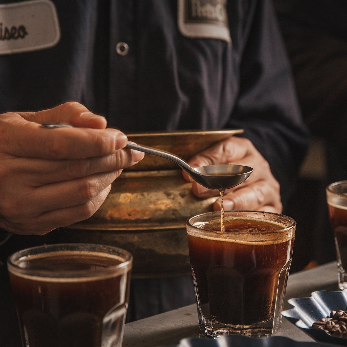 Man holding spoon above a coffee cup
