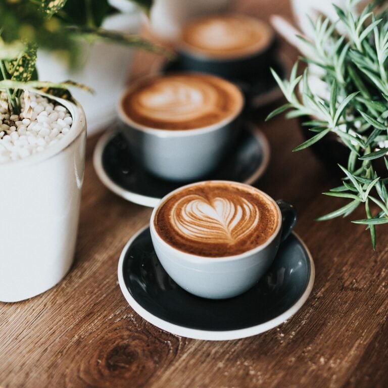 Two cappuccino cups with coffee art on a table